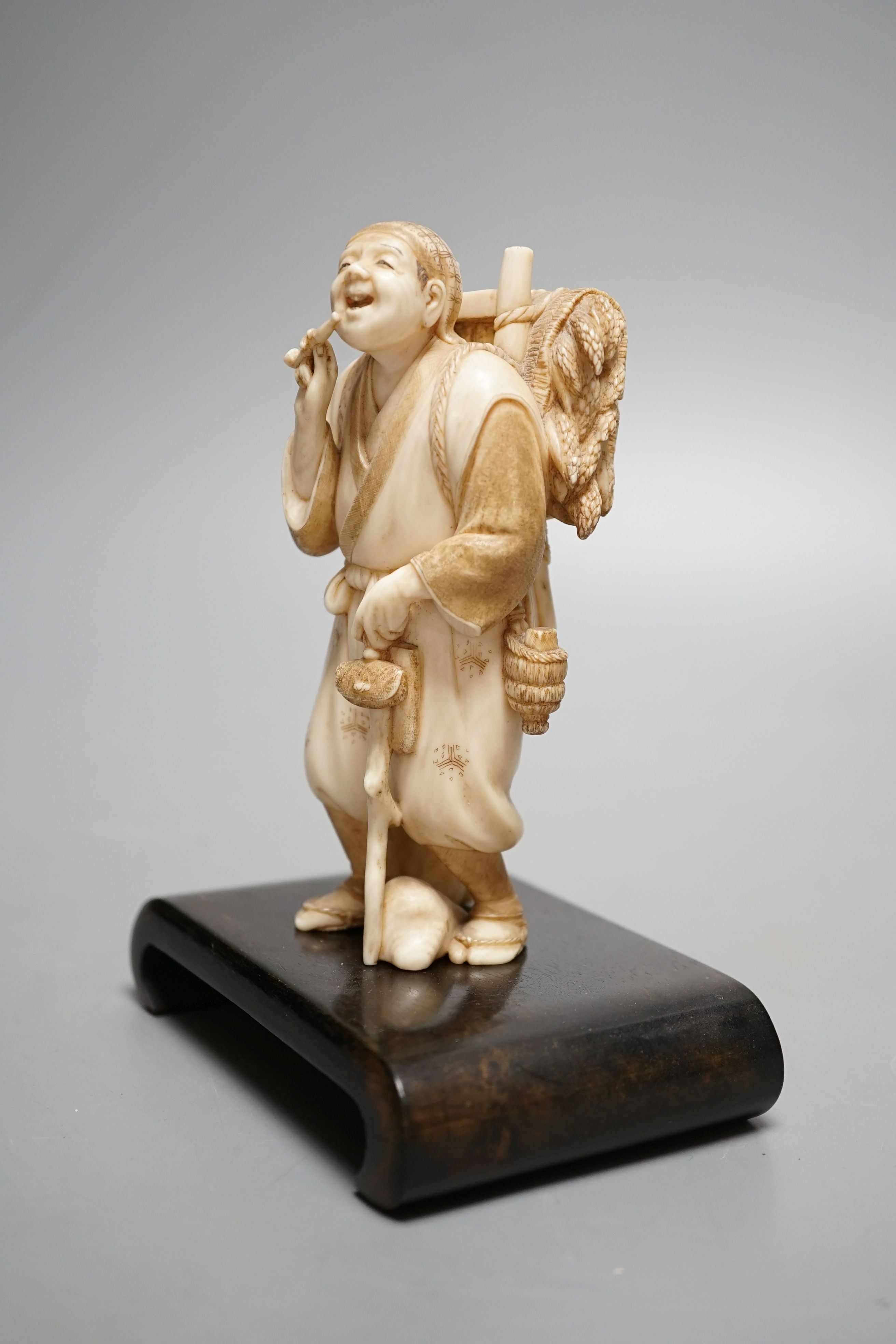 A Japanese ivory figure of a farmer smoking a pipe, Meiji period, signed - 12cm tall